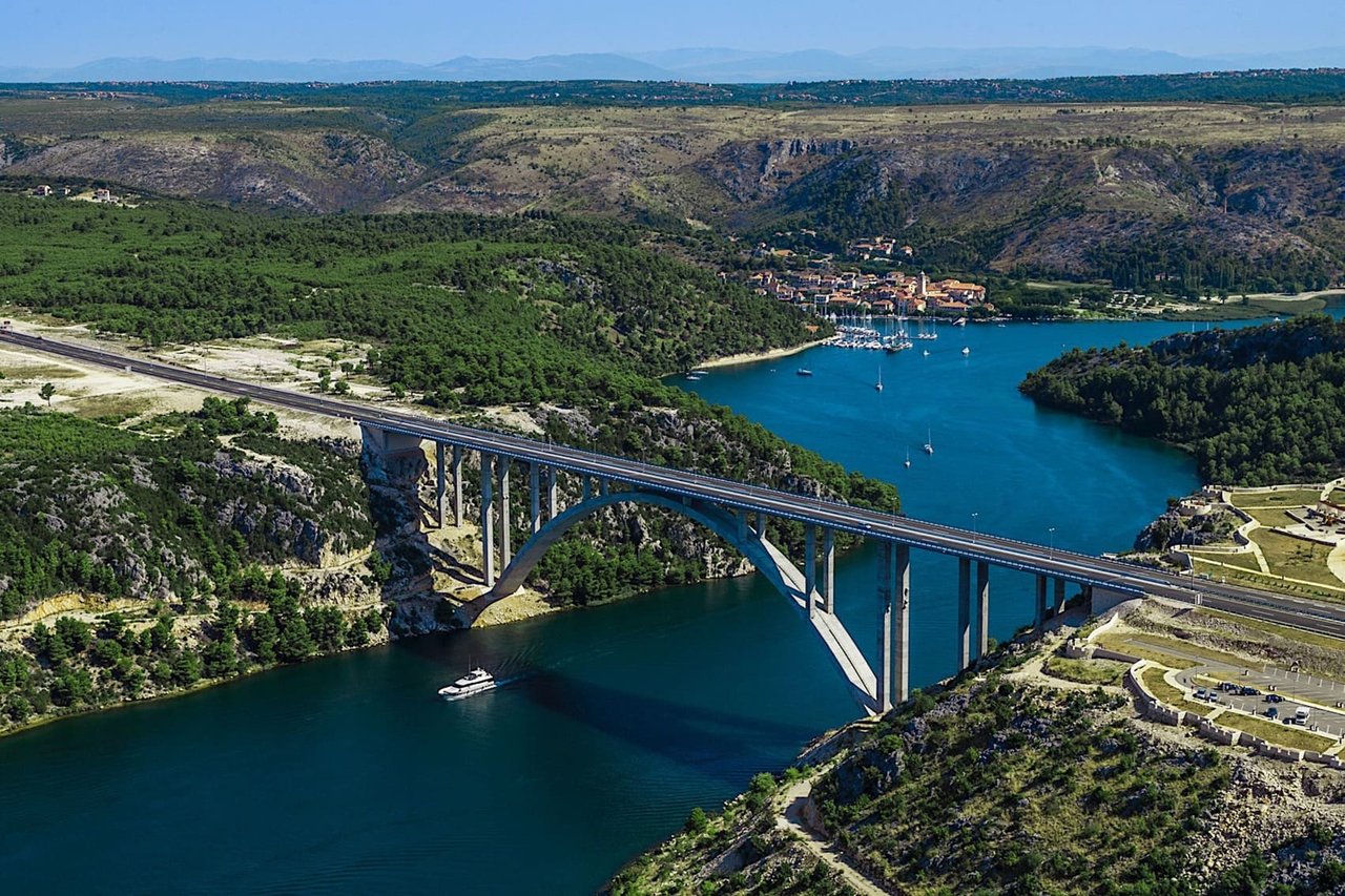 Aerial view of a bridge over a river canyon with coastal town and marina in Croatia