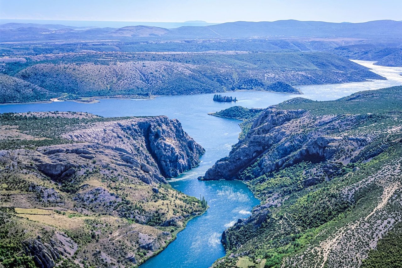 Aerial view of river canyon with rocky cliffs and blue water surrounded by untouched nature in Croatia
