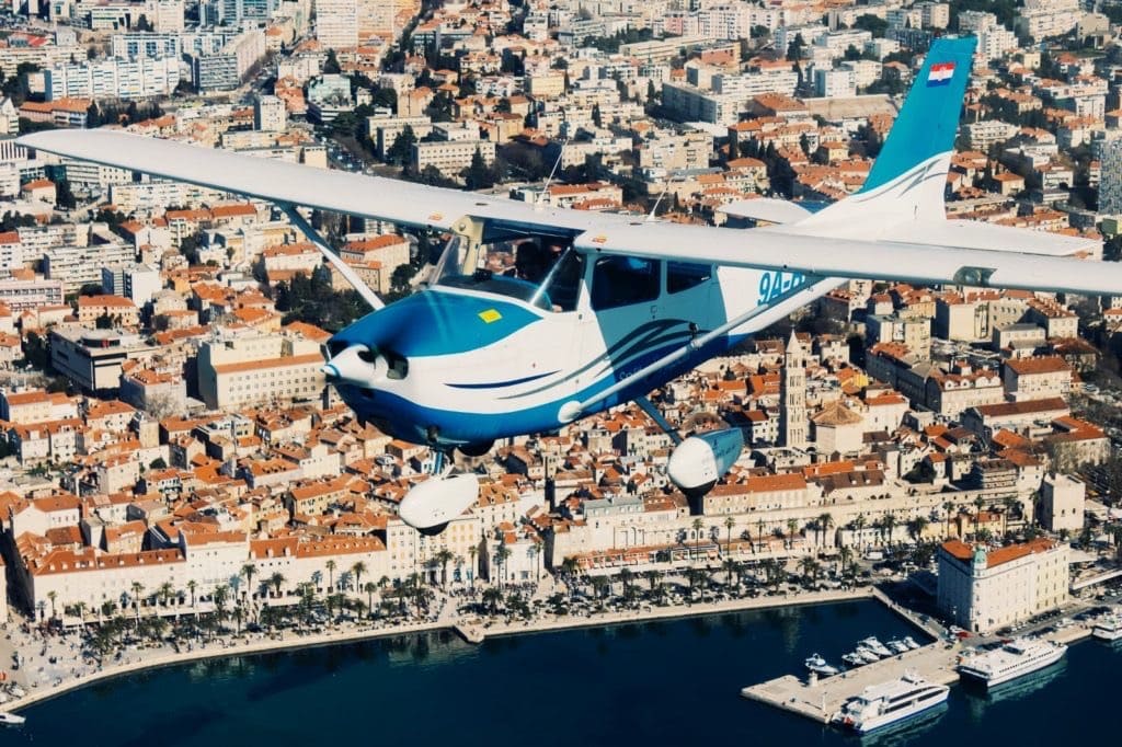 Small airplane flying over Split city and waterfront promenade on the Adriatic coast, Croatia