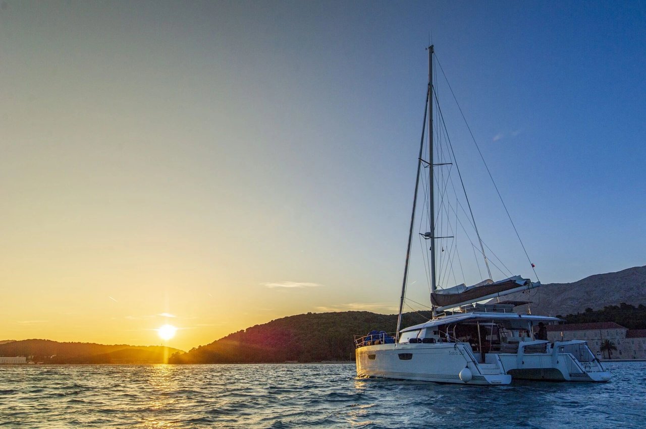 Luxury sailing catamaran at sunset on the Adriatic Sea near the Dalmatian islands of Croatia, a perfect moment of relaxation during a private sailing holiday.