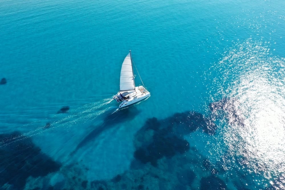 uxury sailing catamaran gliding across the turquoise Adriatic Sea in Croatia, aerial view of a peaceful Dalmatian islands sailing experience.