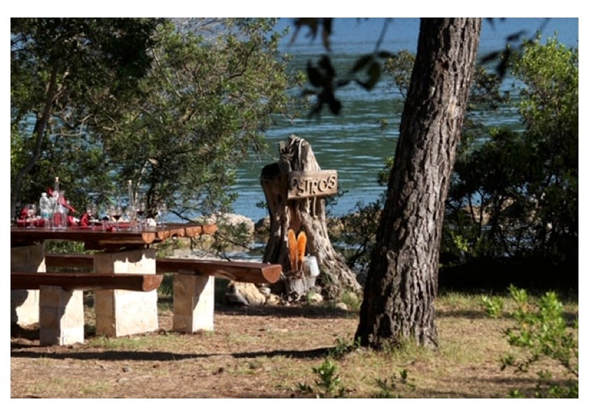 Seaside tasting setup with wooden table and Ostrog peninsula sign overlooking Ston Bay, Croatia