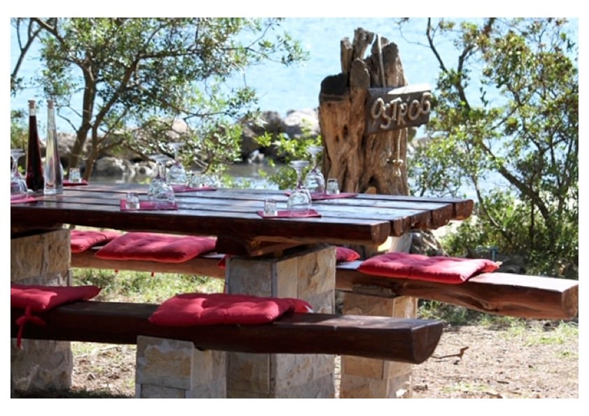 Private seaside dining setup with wooden table and red cushions on Ostrog peninsula, Ston Bay, Croatia